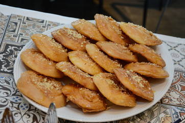 A tasty and sweet plate full of fresh traditional Moroccan handmade Brewat sweets on a fine white fabric surface ready for the celebration of EId Al-Adha