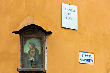 a poetic glimpse on piazza Santo Spirito heart of the popular San Frediano district of Florence with a small tabernacle in the foreground