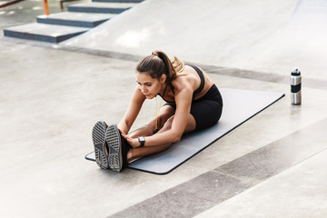 Fototapeta na wymiar Photo of beautiful sportswoman doing exercise on mat while working out