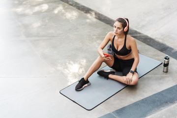 Photo of beautiful sportswoman using cellphone while working out