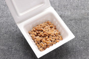 Natto, fermented soybeans in styrofoam container on gray background