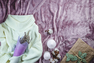 Women fashion cloth, accessories and office equipment. Flat lay female casual style look with warm white sweater on purple background. Top view.