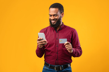 Black male holding credit card and cellphone at studio