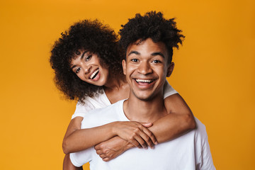 Image of funny african american couple laughing while piggyback riding
