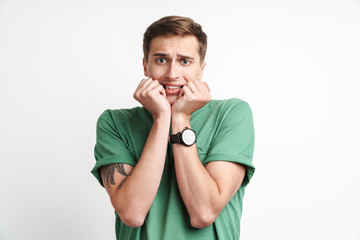 Image of young caucasian man in basic t-shirt being scared and shocked