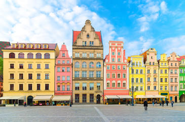 Row of colorful traditional buildings with multicolored facades on cobblestone Rynek Market Square in old town historical city centre of Wroclaw, blue sky background, Poland - obrazy, fototapety, plakaty