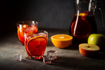 Refreshing red wine sangria or punch with fresh fruits in glasses and pincher on black background