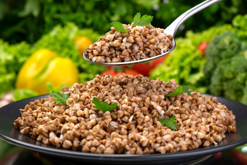 Cooked buckwheat porridge, served with herbs and vegetables on black plate