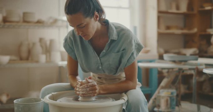 Young artist in the pottery studio making bowl with her hands, handmade creative artist
