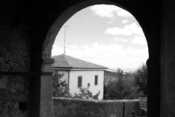 Glimpse of the town of Capalbio, Tuscany, Italy. Dark sky, black and white photo.
