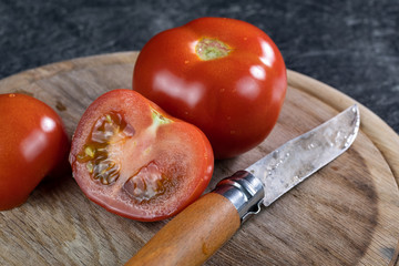 Aufschnittene saftige rote Tomaten, auf einem Holzbrettchen mit einem Messer