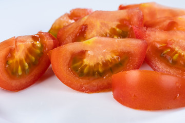 Aufeschnittene saftige rote Tomaten auf einem wei&szlig;en Teller