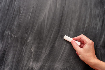 Person using white chalk on a blackboard