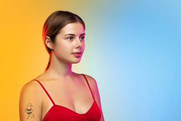 Calm. Close up caucasian young woman's portrait on gradient studio background in neon. Beautiful female model in casual style. Concept of human emotions, facial expression, youth, sales, ad.