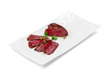 Thin pieces of sliced sausage on white plate isolated on white