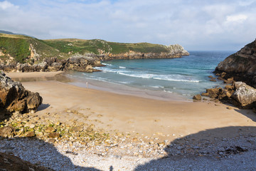 Fototapeta na wymiar Las Fuentes beach on the coast of Cantabria in Spain seen from above on a sunny day with waves