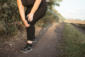Woman touching her leg, got a knee trauma at outdoor jogging. Sports injury, health care, sports, jogging, medical concept