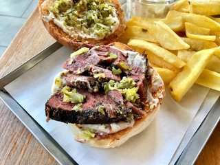 Pastrami Burger with Mustard and Pickles served with Potatoes.