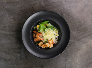 Caesar salad with shrimps in black plate