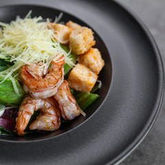 Caesar salad with shrimps in black plate