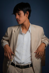 Young male model wearing khaki blazer/suit with white shirt over dark grey background