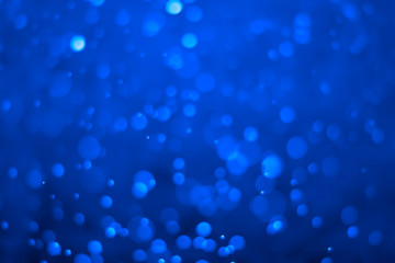 Blue glitter vintage lights background. Blue bokeh on black background.