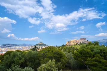 Fototapeta na wymiar Iconic view of Acropolis hill and Lycabettus hill in background in Athens, Greece from Pnyx hill in summer daylight with great clouds in blue sky.