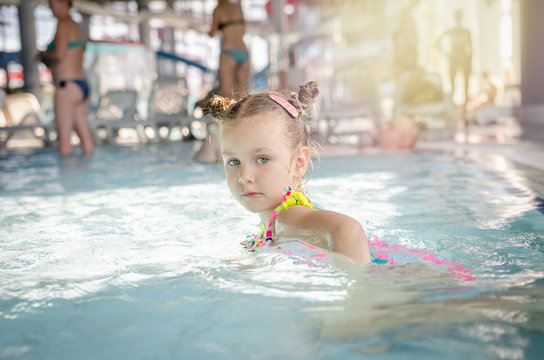little beautiful girl playing with a foam noodle in a indoor pool. rest in the water park	
