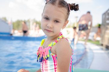 little beautiful girl swimming with a foam noodle in a outdoor pool. summer vacation in the water...