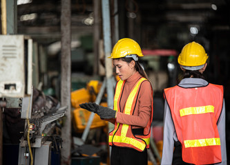 Portrait of young  Asian technician women or industrial worker with hardhat and vest working machine in Factory of manufacturing place  on Background