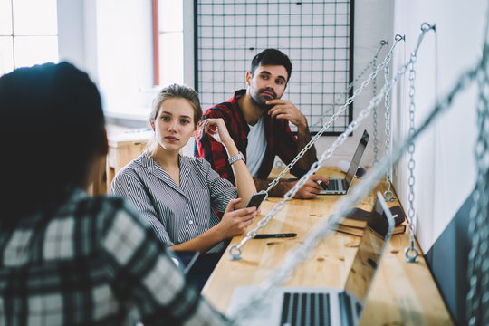 Group of young male and female IT professionals enjoying workshop of skilled software developer and thoughtful listening useful information about programming, students making presentation using laptop