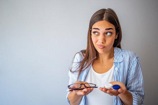 Girl Comparing Contacts To Eyeglasses For Vision Correction. Woman Choosing Between Contact Lenses And Glasses In Optic Store. Woman Thinking To Choose Contact Lenses Over Eyeglasses