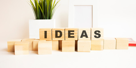 Wooden cubes with letters on a white table. White background with photo frame and house plant.