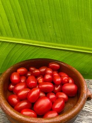 Tomatoes in Bowl on wooden table with banana leaf