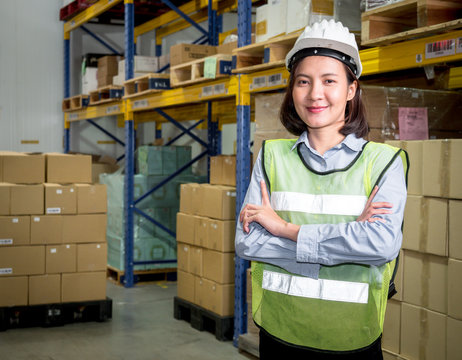 Portrait Of A Young Woman Warehouse Worker Is Smiled Happily While Lifting The Goods To Arrange For Delivery To The Customers Inside The Warehouse. Real People And Real Bodies Concept