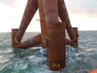 crane lifts tripod to the sea on a windy field