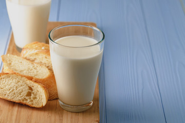 Glass of milk with sliced baguette on wooden board