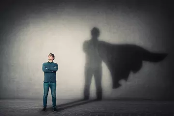 Foto op Canvas Brave man keeps arms crossed, looks confident, casting a superhero with cape shadow on the wall. Ambition and business success concept. Leadership hero power, motivation and inner strength symbol. © 1STunningART
