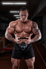 Fototapeta na wymiar A man trains in the gym. Athletic man trains, pumping his biceps