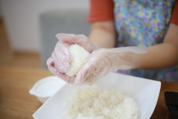 おにぎりを握る女性の手元 © yamasan