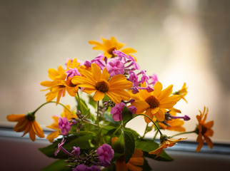 Summer bouquet on the background of the window. Lilac phlox and yellow daisies. Soft focus.