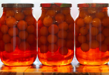 Three large cans, canned plums - compote. Yellow, orange, red. Soft focus.