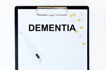 On the table are pills, a thermometer, leaves and a notebook with the inscription -Dementia. The concept of medicine.