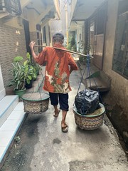 Homme transportant des colis dans une ruelle de Jakarta, Indonésie