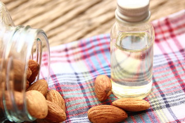 close up roasted organic brown almond seed  on plaid with sweet almond oil refined in the bottle.
