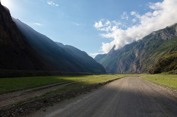 Fototapeta premium a canyon with a dirt road among the fjords. a ray of light illuminates a gorge in a beautiful mountain valley.