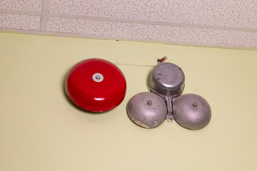 A red fire alarm in a building near a wall.