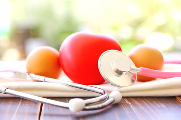stethoscope with red heart ,eggs on white cloth with blur background .medically eating egg everyday  helps to reduce heart problem.