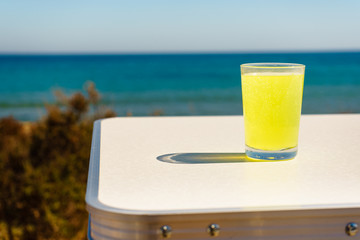Citrus drink in glass on sea shore