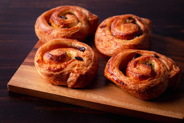 puff pastry cinnamon rolls with custard and raisins dark  wooden background. Top view, space.
